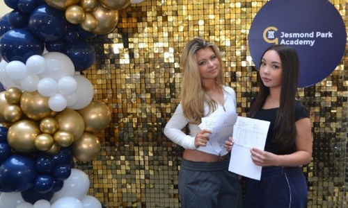 Two female students posing for a photograph, holding their GCSE results.